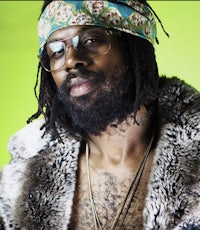 a man with glasses and dreadlocks wearing a furry jacket