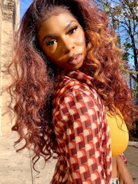 a woman with long curly hair posing on a sidewalk