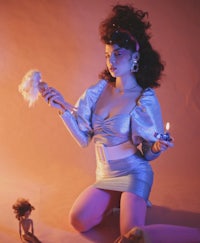 a woman in a silver dress posing with dolls