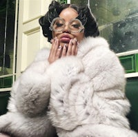 a woman in a white fur coat sitting on a bench