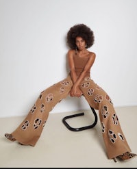 a woman is sitting on a chair wearing tan leopard print pants