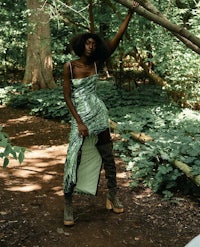 a woman in a green dress posing in the woods