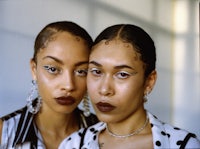 two women posing in front of a mirror