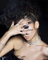 a woman with black nails covering her face