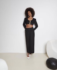 a black woman in a crop top and skirt standing in a white room